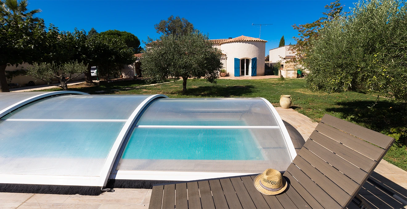 Un technicien mesure la largeur d'un bassin de piscine près d'un abri fixe.